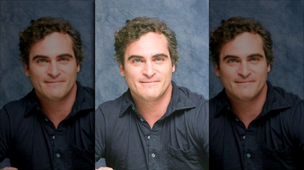 Joaquin Phoenix in a dark button-up shirt, posing with a small smile