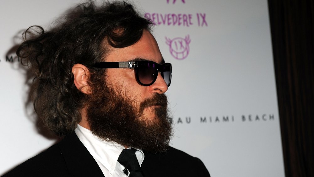 Joaquin Phoenix in a black suit, beard, and sunglasses in 2009