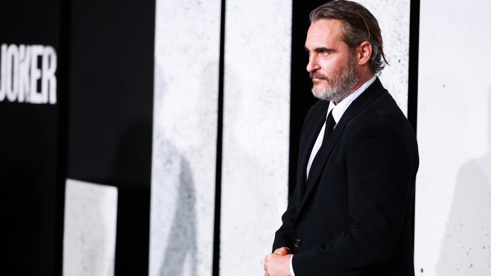 Joaquin Phoenix facing photographers in a black suit at the Joker premiere in 2019