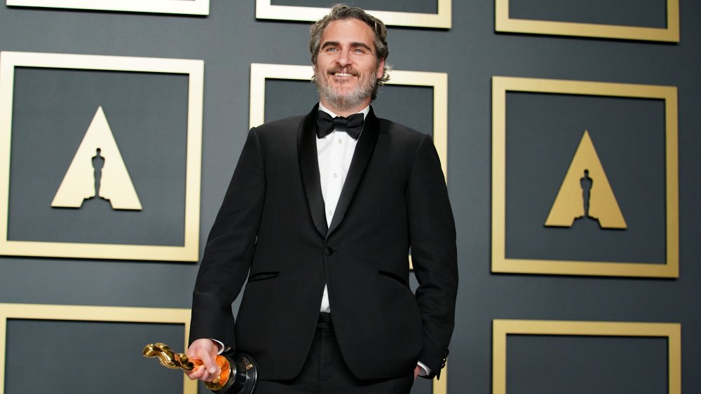 Joaquin Phoenix smiling while holding his Oscar award in 2020