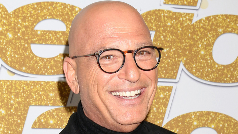 Howie Mandel smiles, wearing glasses