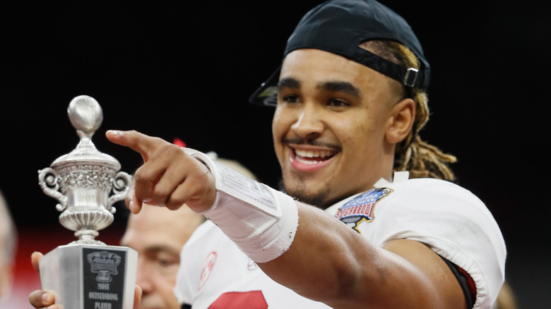 Jalen Hurts holds trophy while pointing and smiling