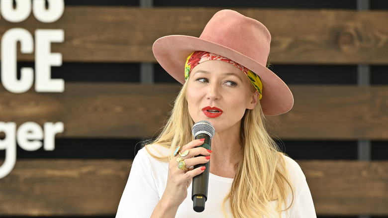 Jewel sitting and holding a microphone