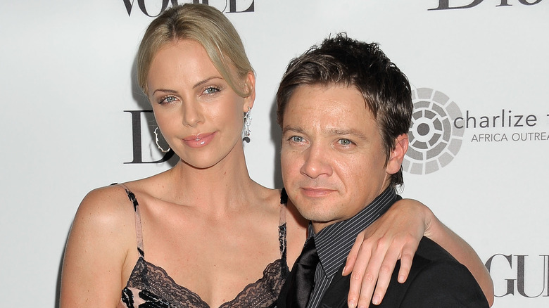 Charlize Theron with arm draped around Jeremy Renner