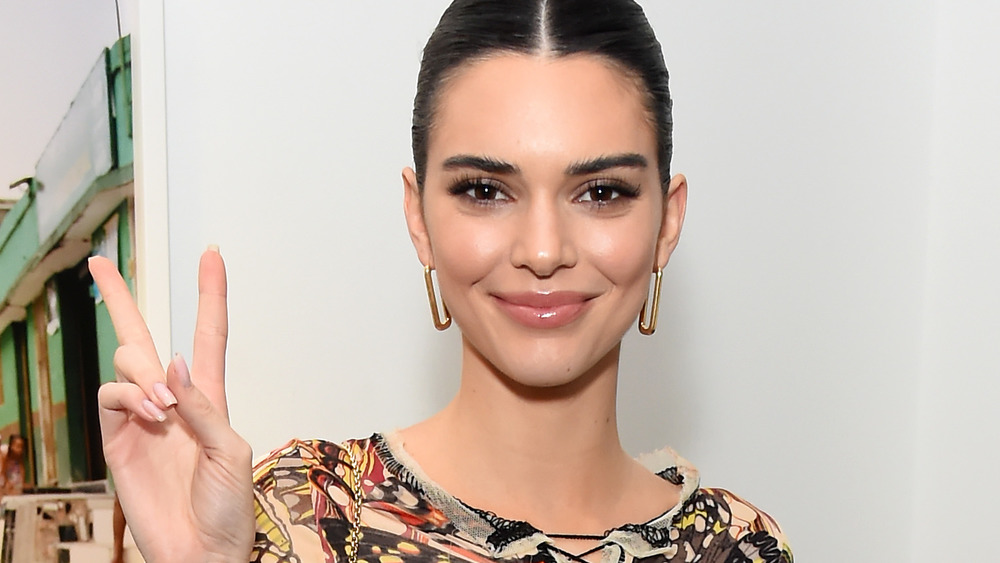 Kendall Jenner smiling and giving the peace sign