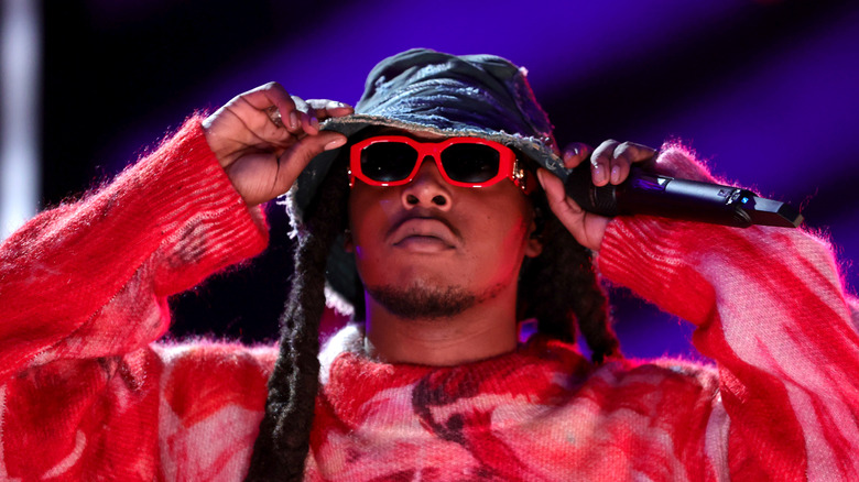 Takeoff in bucket hat, posing on stage