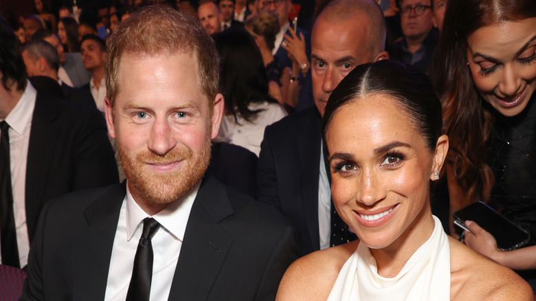 Prince Harry and Meghan Markle sitting in an auditorium