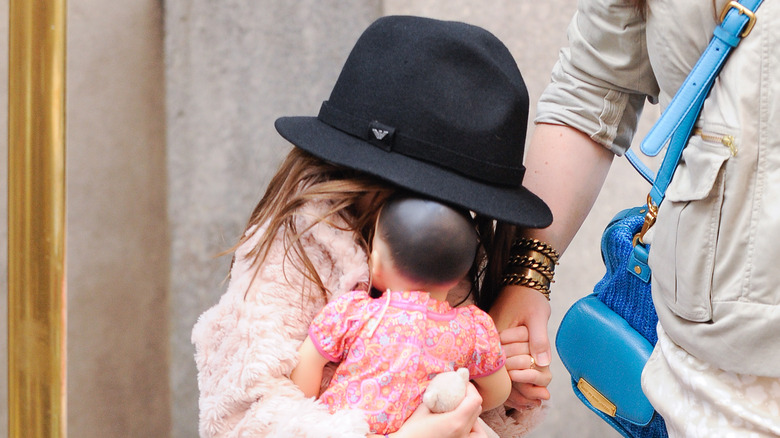 Suri Cruise hiding behind doll