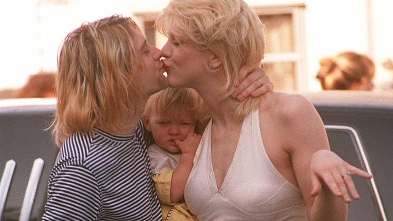 Kurt Cobain and Courtney Love kissing with Frances Bean