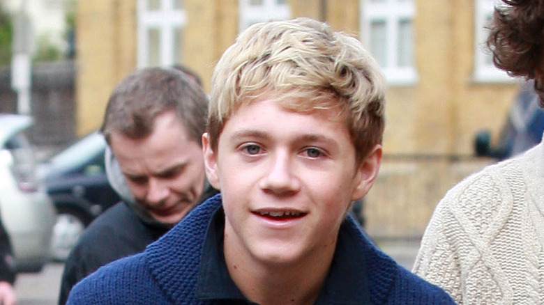 Young Niall Horan smiling on a street