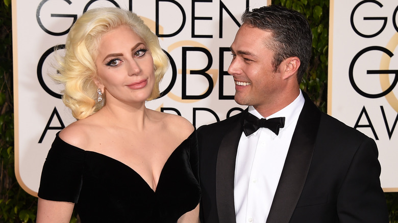 Lady Gaga wearing a black velvet gown and Taylor Kinney in a black tuxedo and bow tie