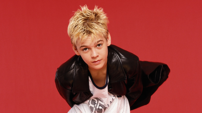 A teenage Aaron Carter in front of red background