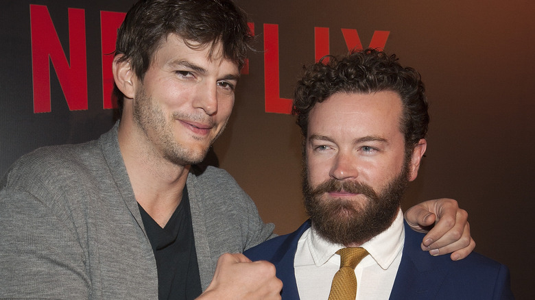 Ashton Kutcher smiling with and punching Danny Masterson's shoulder