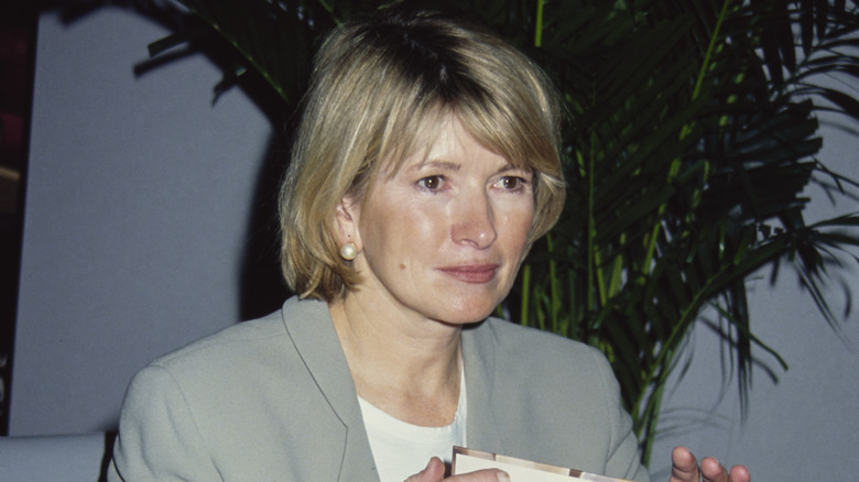 Martha Stewart glances at her audience while signing a book.