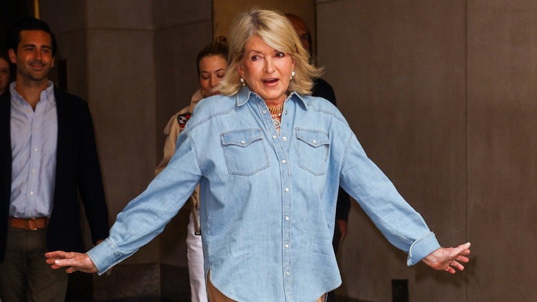 Martha Stewart walks animatedly in denim shirt.