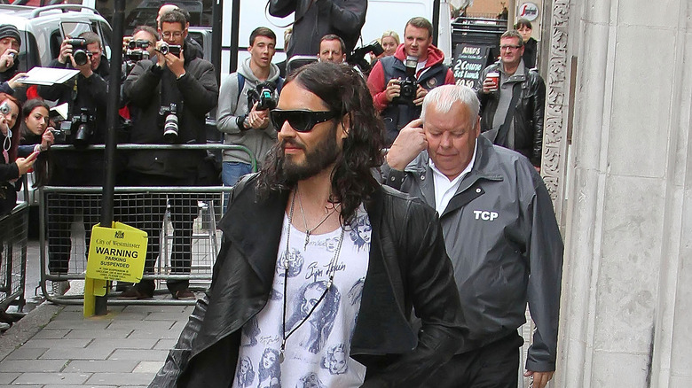 Russell Brand surrounded by photographers