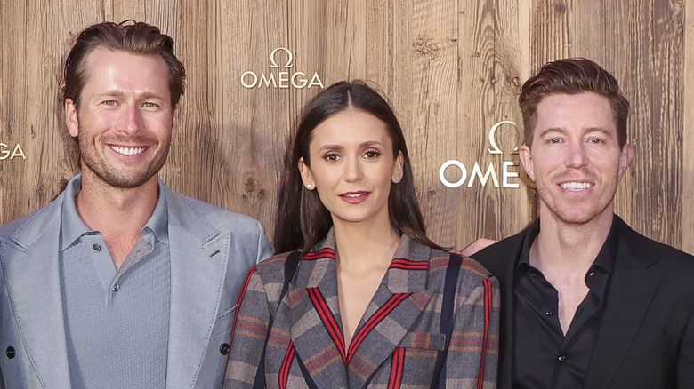 Nina Dobrev between Glen Powell, Shaun White, all posing