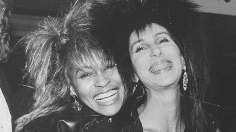 Tina Turner hugging Cher from behind both smiling