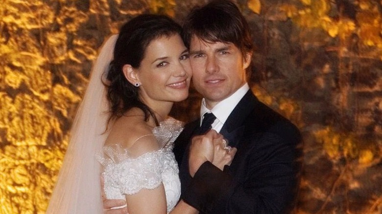 Katie Holmes and Tom Cruise holding hands at their wedding