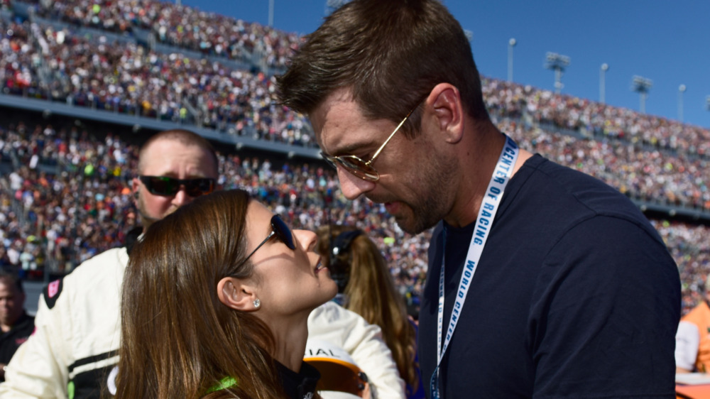 Danica Patrick and Aaron Rodgers embracing at the racetrack