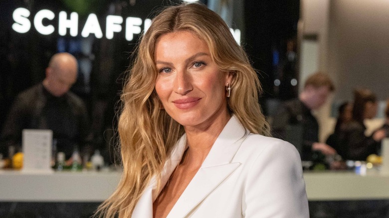 Gisele Bundchen smiles in a white suit