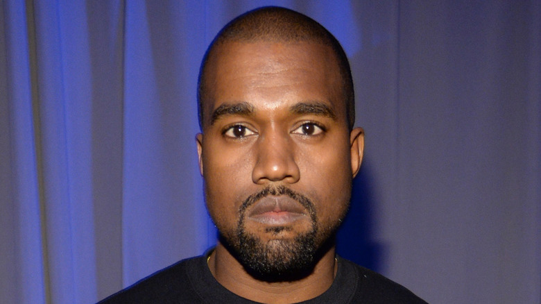 Kanye West wearing a black shirt, stares at camera