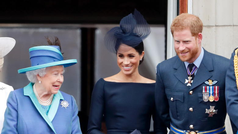 Queen Elizabeth II speaking to Meghan Markle and Prince Harry at an event