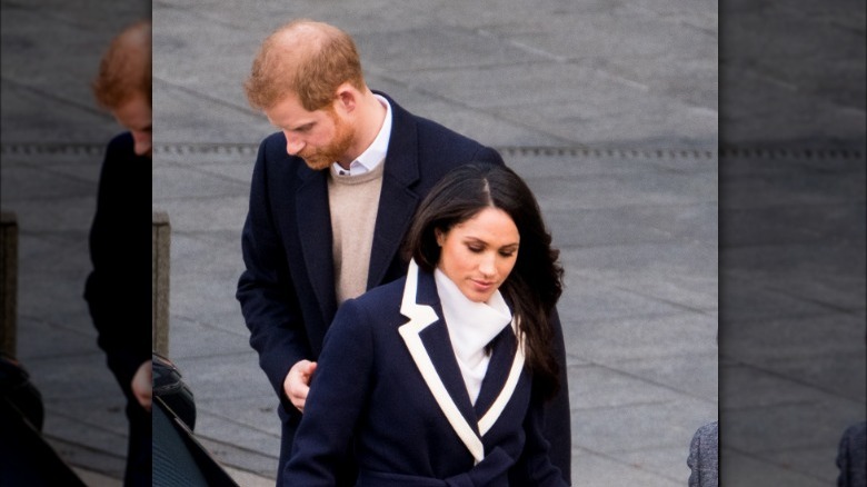 Prince Harry and Meghan Markle looking concerned at an event