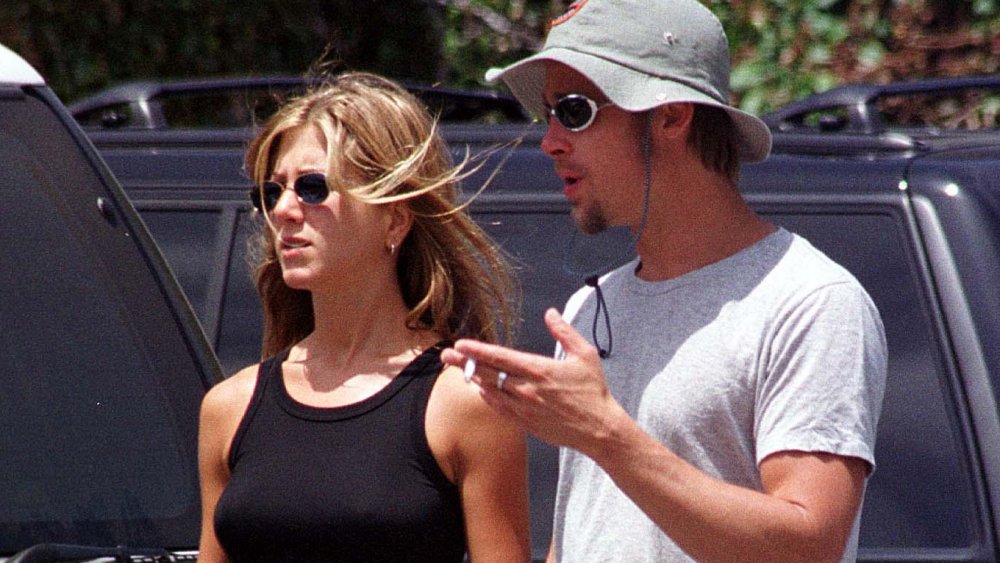 Jennifer Aniston and Brad Pitt, both wearing sunglasses, talking while walking in a parking lot