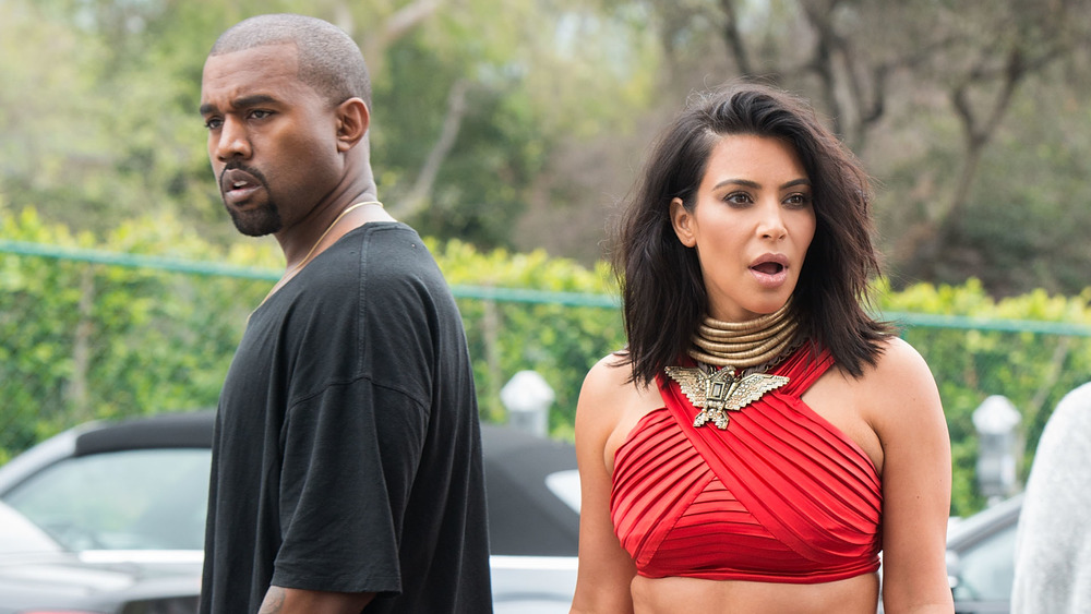 Kanye West and Kim Kardashian backs to one another standing outside