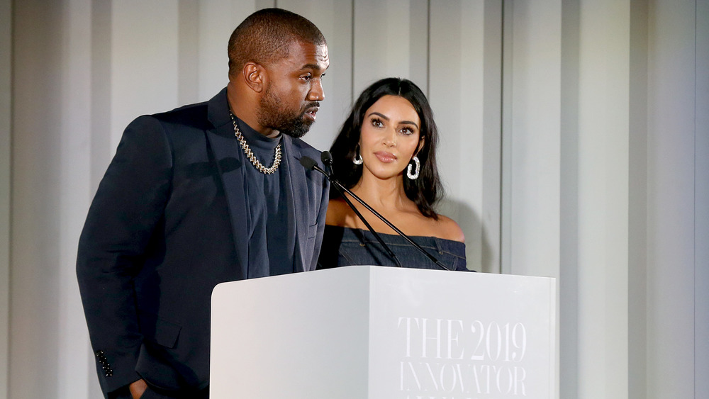 Kanye West and Kim Kardashian standing at a podium