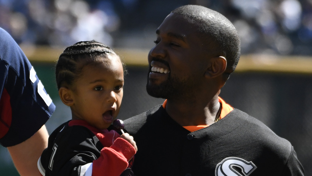 Kanye West carrying Saint West and smiling