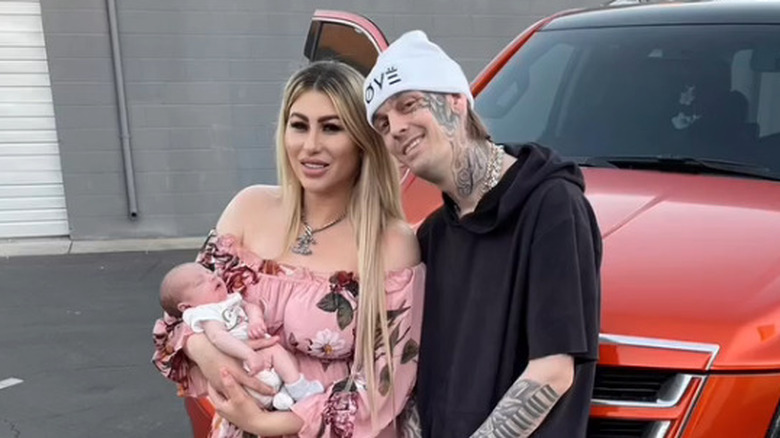 Melanie Martin and Aaron Carter pose next to a car with their son, Prince