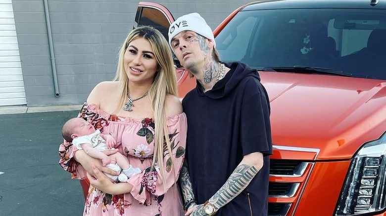 Aaron Carter and Melanie Martin hold Prince in front of car