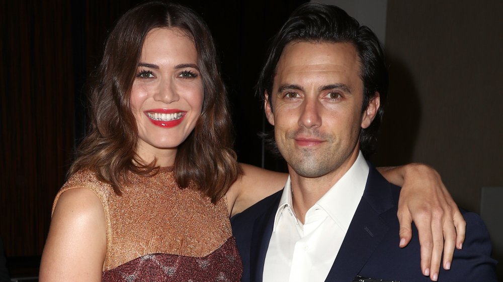 Mandy Moore smiling with her arm around a grinning Milo Ventimiglia