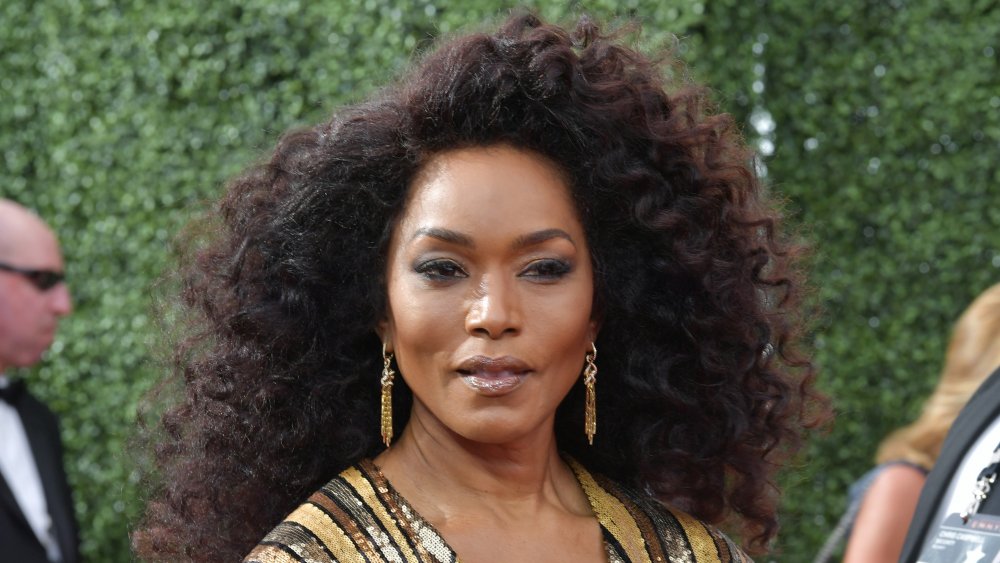 Angela Bassett in a sparkly gold striped dress, posing with a serious expression