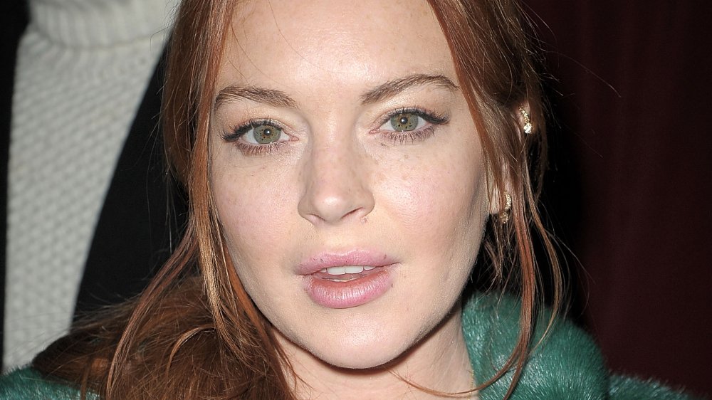 Lindsay Lohan in a green coat, looking straight at the camera with a neutral expression