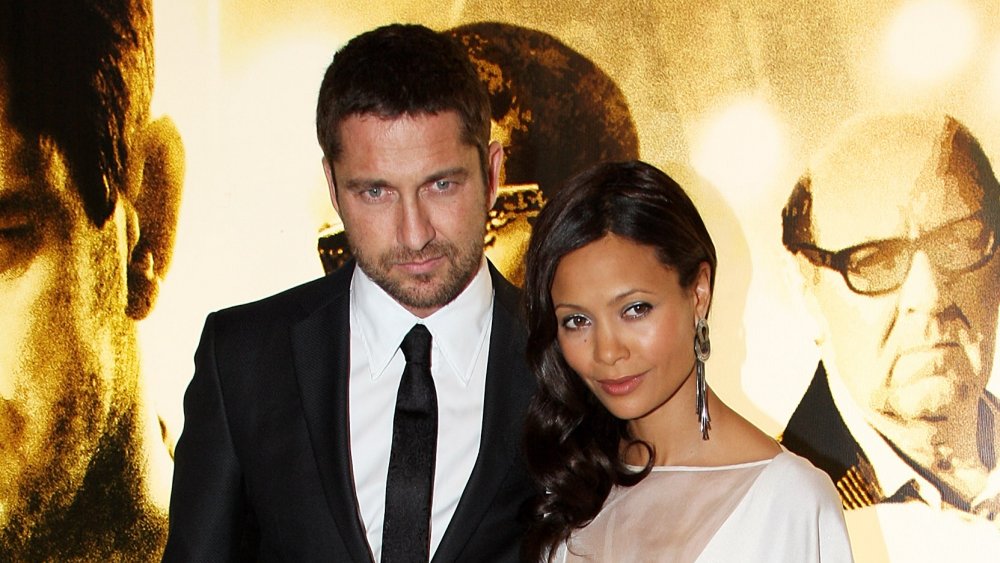 Gerard Butler in a classic black suit, Thandiwe Newton in a white dress, posing with each other at their movie's premiere