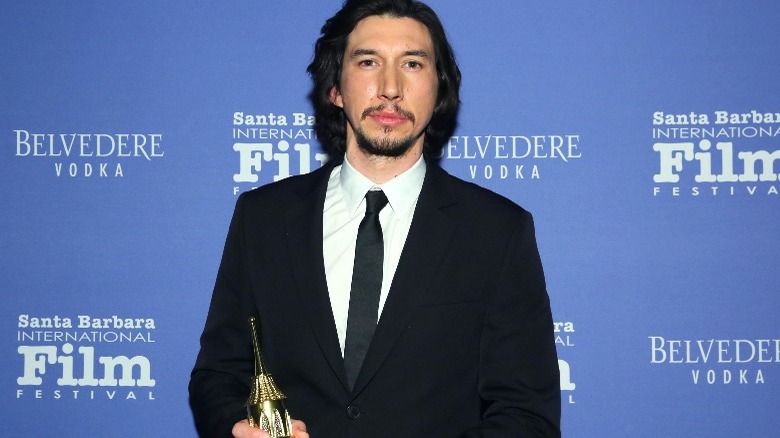 Adam Driver holding an award at a film festival