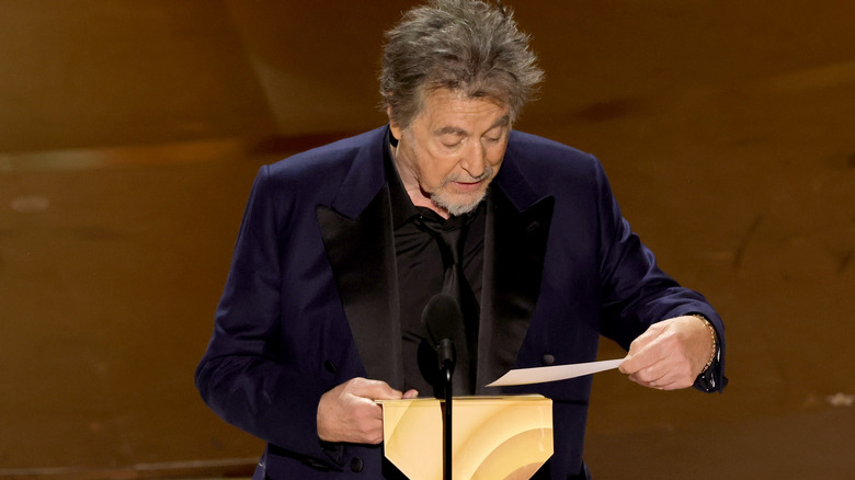 Al Pacino taking paper out of envelope at microphone