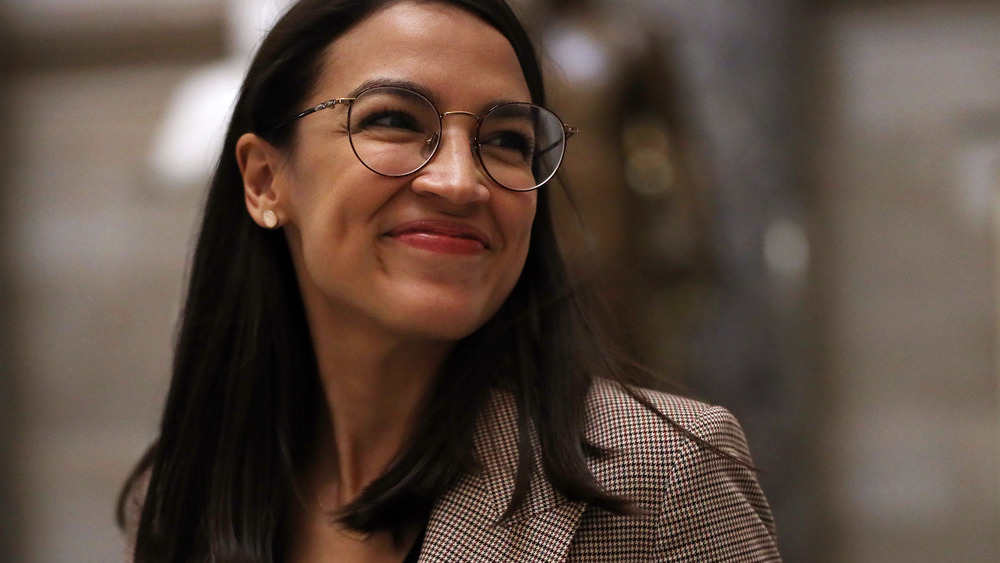 Alexandria Ocasio-Cortez smirking while looking over her shoulder