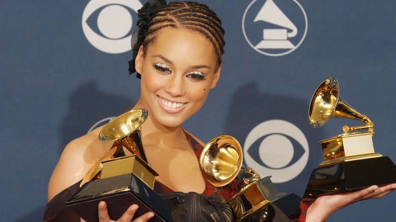 Alicia Keys smiles while holding Grammy trophies