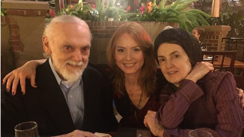 Alicia Witt smiling with arms around her mother and father