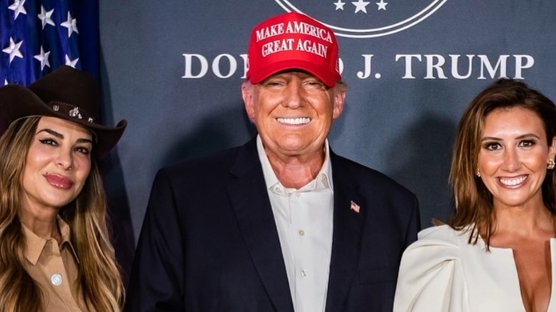 Siggy Flicker posing with Donald Trump and Alina Habba