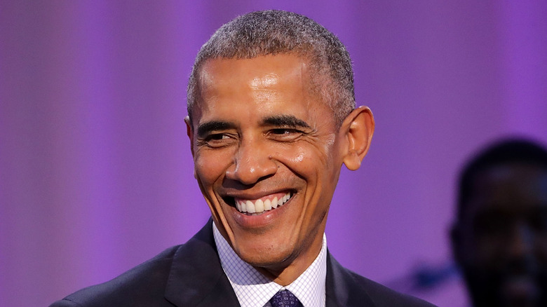 Barack Obama smiles against purple background