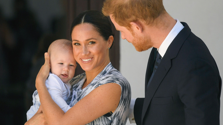 Meghan Markle holding Prince Archie as Prince Harry watching