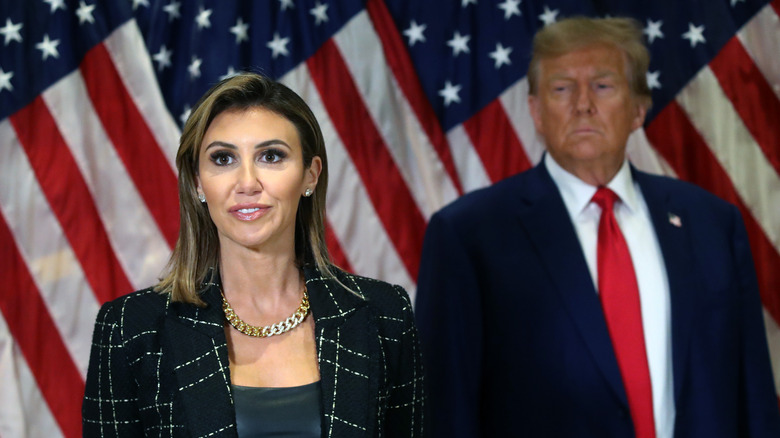 Alina Habba and Donald Trump in front of flags