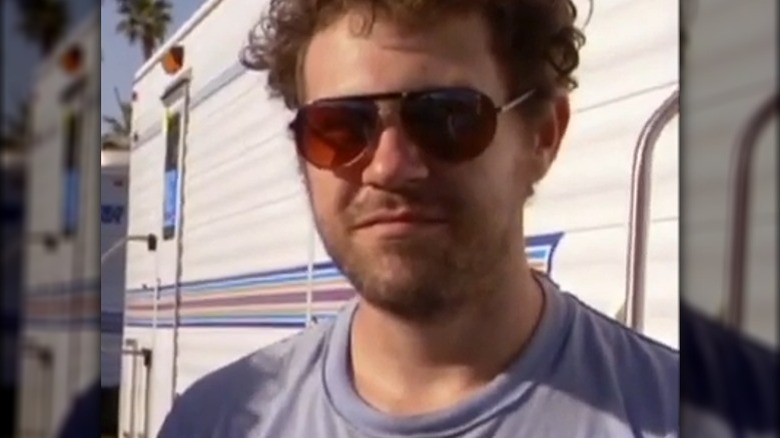 Jeremy Ward wearing sunglasses and t-shirt in front of an RV