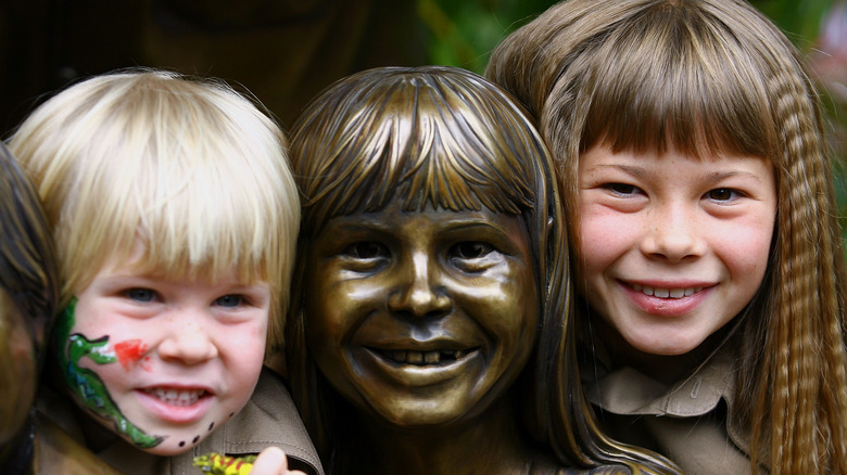 Robert and Bindi Irwin pose with a statue of the family in 2007