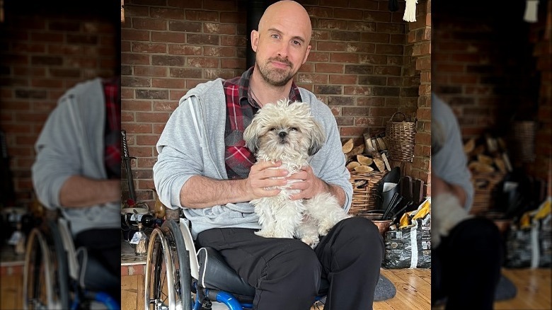 Jonathan Goodwin poses in wheelchair with dog